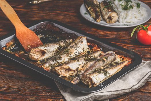 Baked fish carcasses on baking sheet over wooden surface