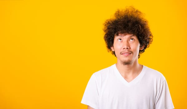 Asian handsome man with curly hair looking up see he hair isolate on yellow background with copy space for text