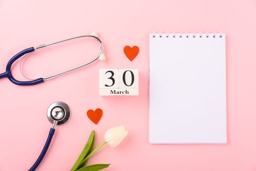 Doctor's Day concept, flat lay top view, equipment medical red heart stethoscope and note book on pink background, care patient in hospital with copy space for text