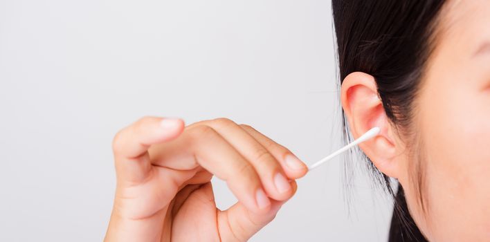 Asian beautiful woman cleaning ear hrt using cotton swab on white background with copy spece for text, healthcare concept