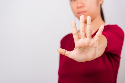 Asian beautiful woman itching her outstretched hand showing stop gesture front face, focus on hand on white background with copy space