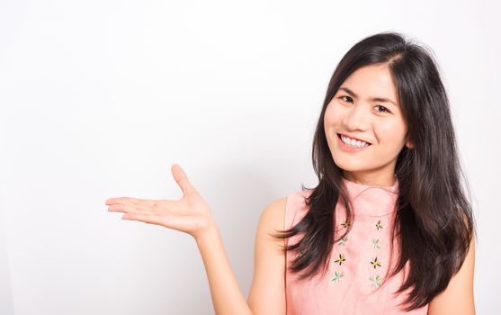 Portrait Asian beautiful young woman standing, She showing hand to presenting product and looking at the camera, shoot photo in a studio on white background, There was copy space