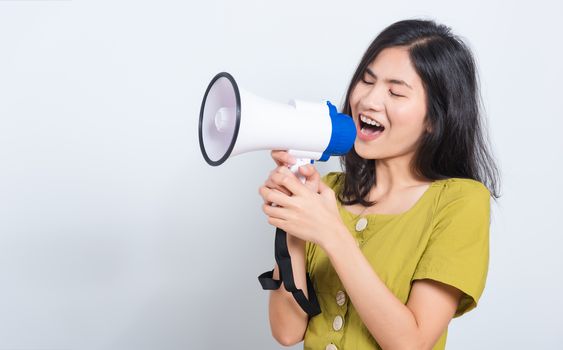 Portrait Asian beautiful young woman standing smile holding and shouting into megaphone looking to space, shoot the photo in a studio on a white background, There was copy space