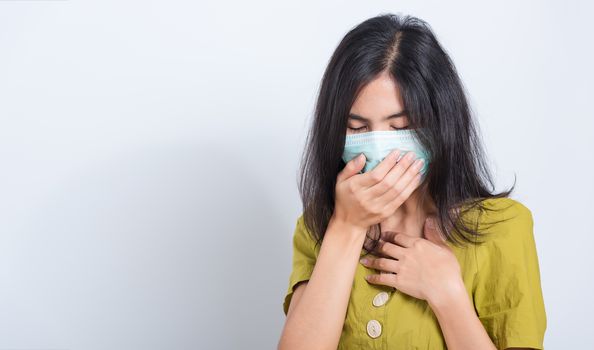 Portrait Asian beautiful happy young woman wearing face mask protects filter dust pm2.5 anti-pollution, anti-smog, and air pollution her sneezing in mask on a white background, with copy space