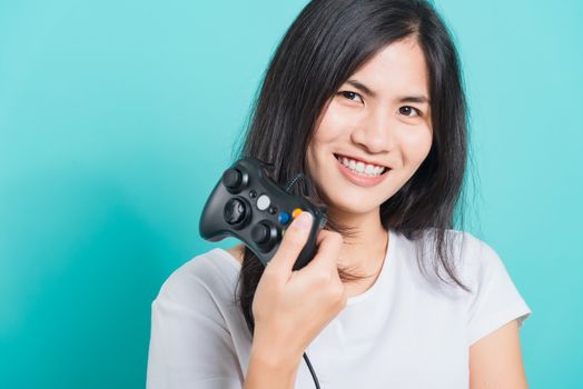 Portrait Asian beautiful happy young woman wear t-shirt gamer with a joystick or gamepad in hands, on blue background