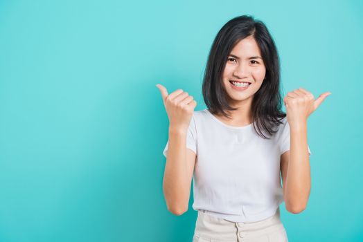 Portrait Asian beautiful happy young woman smile white teeth wear white t-shirt standing successful woman giving two thumbs up gesture, on a blue background with copy space