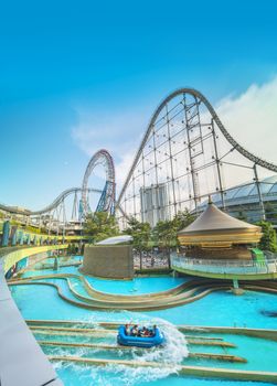 Laqua Tokyo Dome City Mall with its impressive roller coaster integrated in the gallery of its shopping center with a carousel  and water coaster under the summer blue sky.