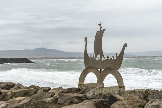 Audur's arrivals viking boat sculpture in front of the stormy sea of Iceland in Porklakshofn