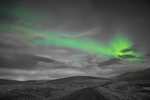 Aurora in Iceland northern lights bright beams rising green over black and white scenery