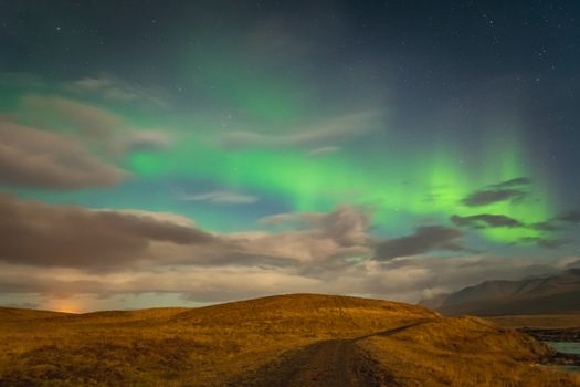 Aurora in Iceland northern lights bright beams rising green over hiking path