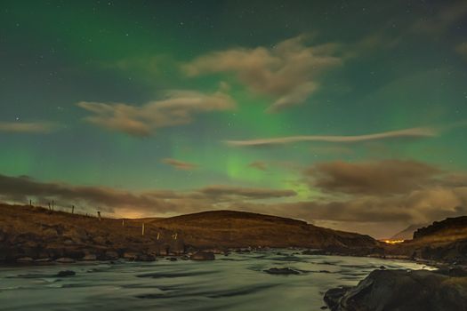 Aurora in Iceland northern lights bright beams rising in green beams reflecting in natural river