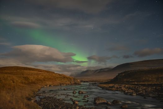 Aurora in Iceland northern lights shining green and reflecting in river