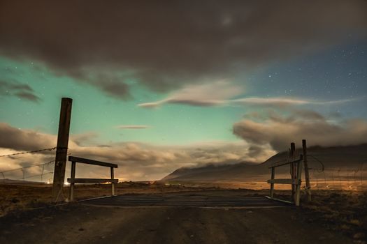 Aurora in Iceland northern lights shining through gaps in clouds over icelandic landscape
