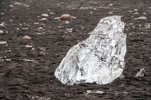 Diamond beach black sand crystal clear piece of ice lying on Atlantic shore