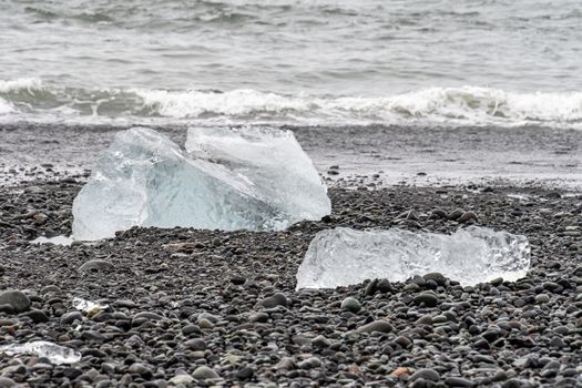 Diamond beach black sand crystal clear pieces of ice lying on dark rocks