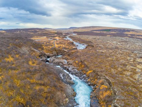 Hraunfossar series of waterfalls barnafoss aerial image of turquoise water streaming down gaps in lava field during fall