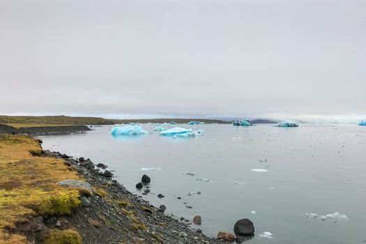 Joekulsarlon Glacier Lagoon deep blue iceberg drifting towards Atlantic shore line
