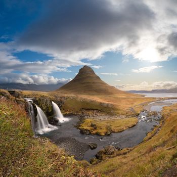 Kirkjufell in Iceland Kirkjufellsfoss waterfall and famous mountain under beautiful shining sun
