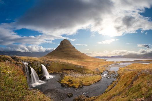 Kirkjufell in Iceland Kirkjufellsfoss waterfall and famous mountain under beautiful sunny and blue sky