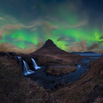Kirkjufell in Iceland Kirkjufellsfoss waterfall and famous mountain under the dancing Aurora
