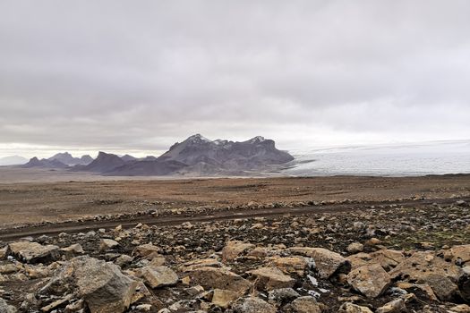 Langjokull Glacier view over bald rock towards ice giant next to epic mountain formation