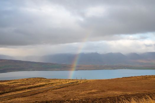 Mountain pass towards Akureyri in Iceland rainbow forming over the fjord