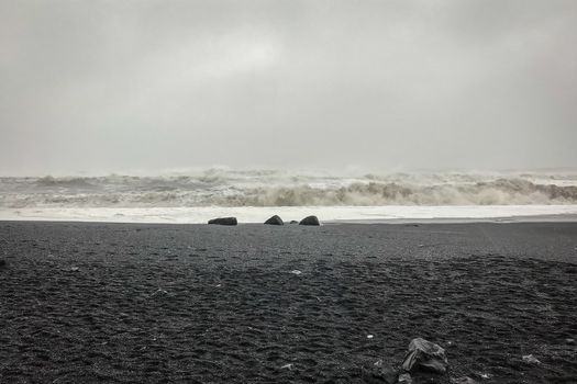 Reynisfjara Beach next to Reynisdrangar huge waves hitting beach during stormy weather and heavy rain
