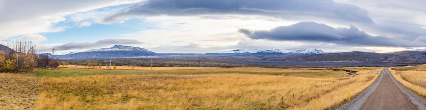 Roadtrip in Iceland panorama of unpaved gravel road in front of massive lava field and the Langjoekull glacier