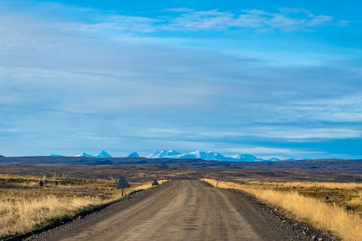 Snaefellsness national park in Iceland scenic landscape and unpaved road in front of snow covered mountains during scenic sunshine