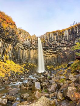 Svartifoss waterfall black basalt columns between autumn colored landscape long exposure photo