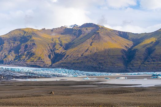 Vatnajoekull glacier in Iceland deep blue ice in front of overgrown mountain