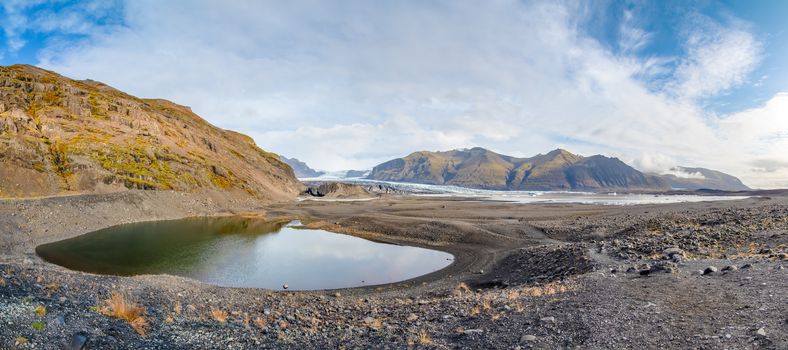 Vatnajoekull glacier in Iceland small glacier lake in front of deep blue eternal ice panorama view