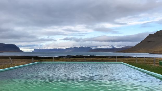 West fjords of Iceland hot spring feeding warm pool with fjord view