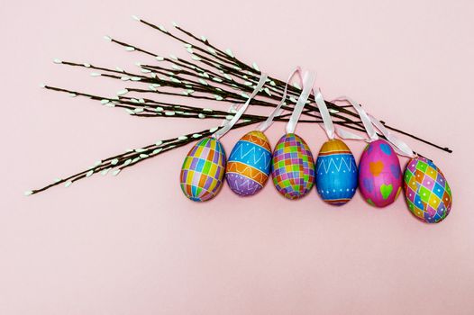 Paper colorful Easter eggs lie on a gently pink background. Easter concept