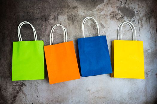 Four colorful shopping bags in a row isolated on dark grunge background