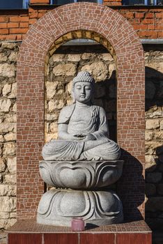 White stone statue of a Buddha on masonry background