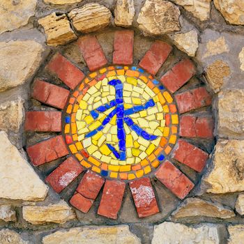 Circular mosaic religious symbol of confucianism on stone wall.