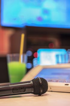 Microphone in Japanese karaoke club, with remote controller, drinks and screen for singing music on stage party. 