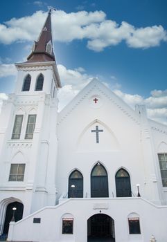 A classic old white plaster church with steeple and arched windows