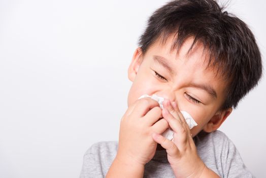 Closeup Asian face, Little children boy cleaning nose with tissue on white background with copy space, health medical care