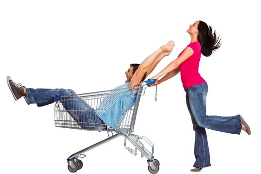 Young couple having fun with shopping cart on white background