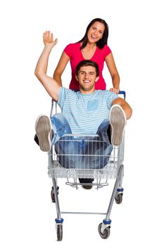 Young couple having fun with shopping cart on white background