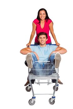 Young couple having fun with shopping cart on white background