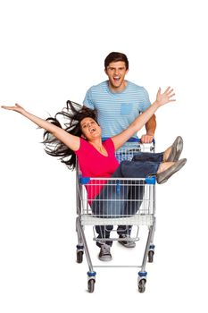 Young couple having fun with shopping cart on white background