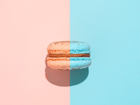 Creative layout with macaron. Trendy light. Two colors macaron or macaroon on duotone coral pink and blue background. Top view or flat lay. Hard light