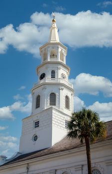A white church steeple with clock rising into a clear blue sky