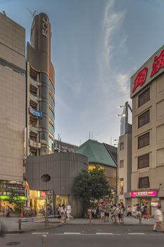 Sunset sky on owl iron mask Shaped of Shibuya Police Station Udagawa Kōban designed by architect Edward Suzuki and opened in April of 1985 in the Inokashira Steet of Shibuya Center Gai which literally means Shibuya Central District. The busiest street once intersected with Shibuya Station, it stretches for 350 meters and incorporates the adjacent streets of Bunkamura, Inokashira and Utagawa into its neighborhood. In 2011 the street was renamed Basketball Street in reference to the holy place of Japanese basketball which is the Yoyogi National Gymnasium to which this street leads. The photo is taken in summer at the Tanabata Star Festival where the portal is adorned with paper decorations in the shape of shooting stars for the occasion.