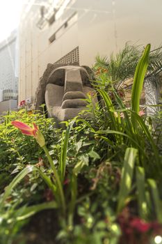 Statue of a Moai head surrounded by tropical flowers at the west exit of Shibuya Station in Tokyo, Japan. This statue was donated in 1980 by the prefecture of Nijima island of Izu archipelago to commemorate the 100 years of the transfer of the island in Tokyo Prefecture.