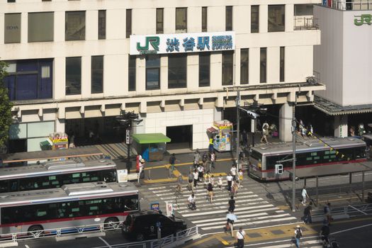 View of the southern exit of Shibuya Station, famous for its moai statue, with buses and taxis stopped at the bus terminal