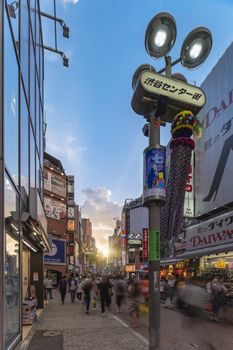 Sunset sky on Shibuya Center Gai Street which literally means Shibuya Central District. The busiest street once intersected with Shibuya Station, it stretches for 350 meters and incorporates the adjacent streets of Bunkamura, Inokashira and Utagawa into its neighborhood. In 2011 the street was renamed Basketball Street in reference to the holy place of Japanese basketball which is the Yoyogi National Gymnasium to which this street leads. The photo is taken in summer at the Tanabata Star Festival where the portal is adorned with paper decorations in the shape of shooting stars for the occasion.